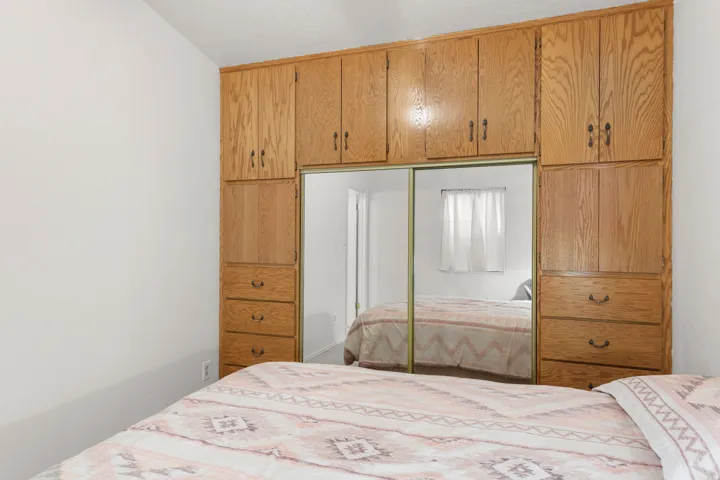 Built-in wood cabinetry with integrated mirrored sliding doors, multiple storage compartments, and wood-finish drawer units