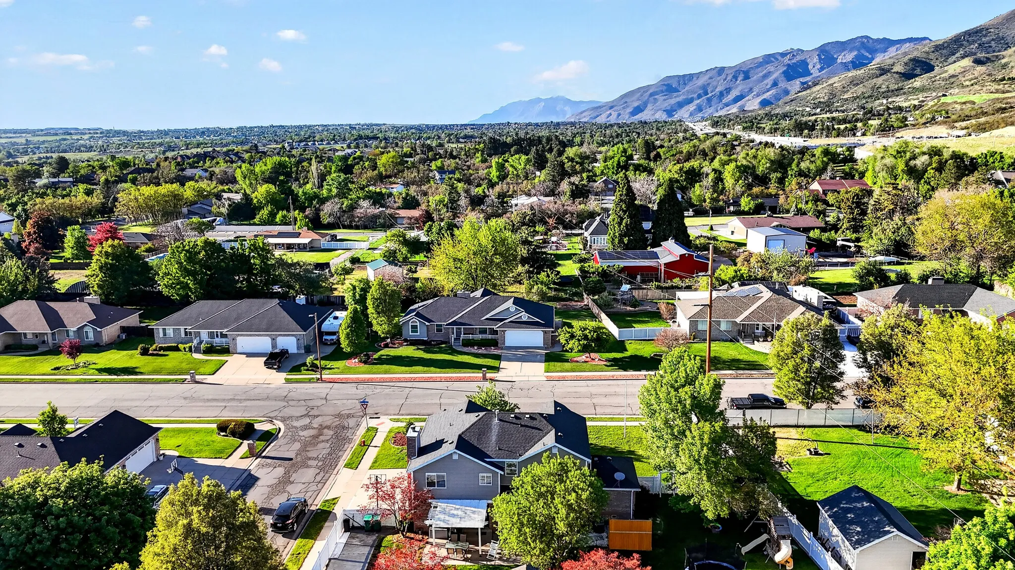 Residential neighborhood featuring single-story and two-story homes, established landscaping, paved streets, and a mountainous backdrop