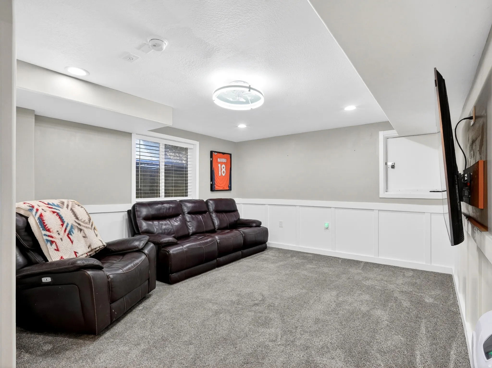 Finished interior space featuring gray carpet flooring, white wainscoting, light gray wall paint, recessed ceiling lighting, and a central ceiling light fixture