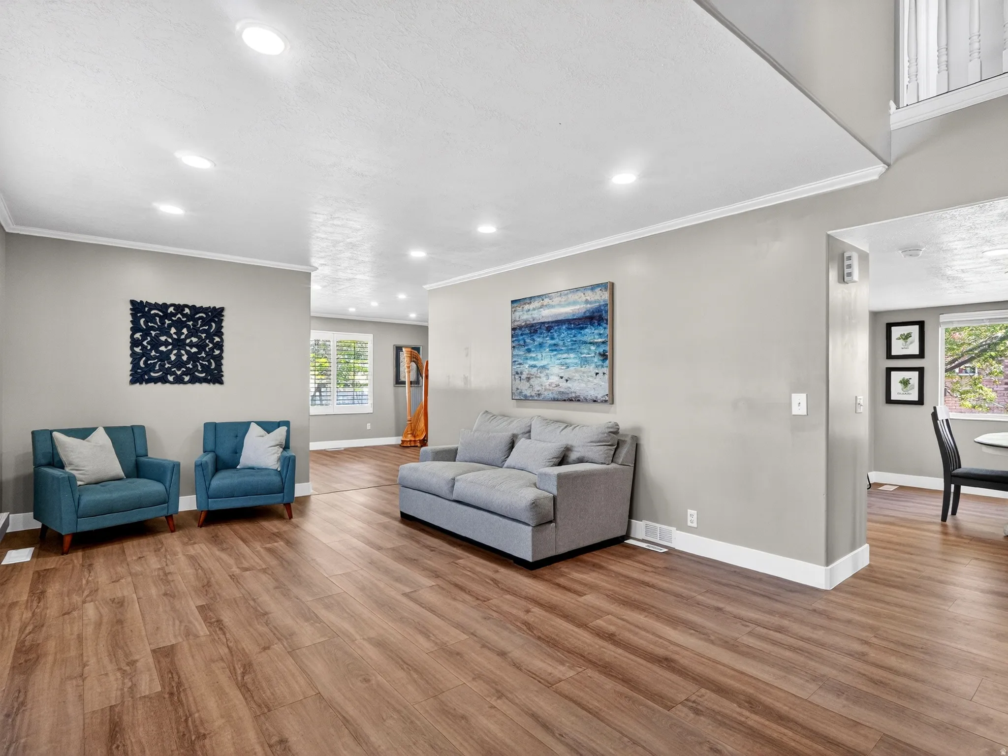 Spacious living area featuring wood-finish flooring, recessed lighting, and crown molding