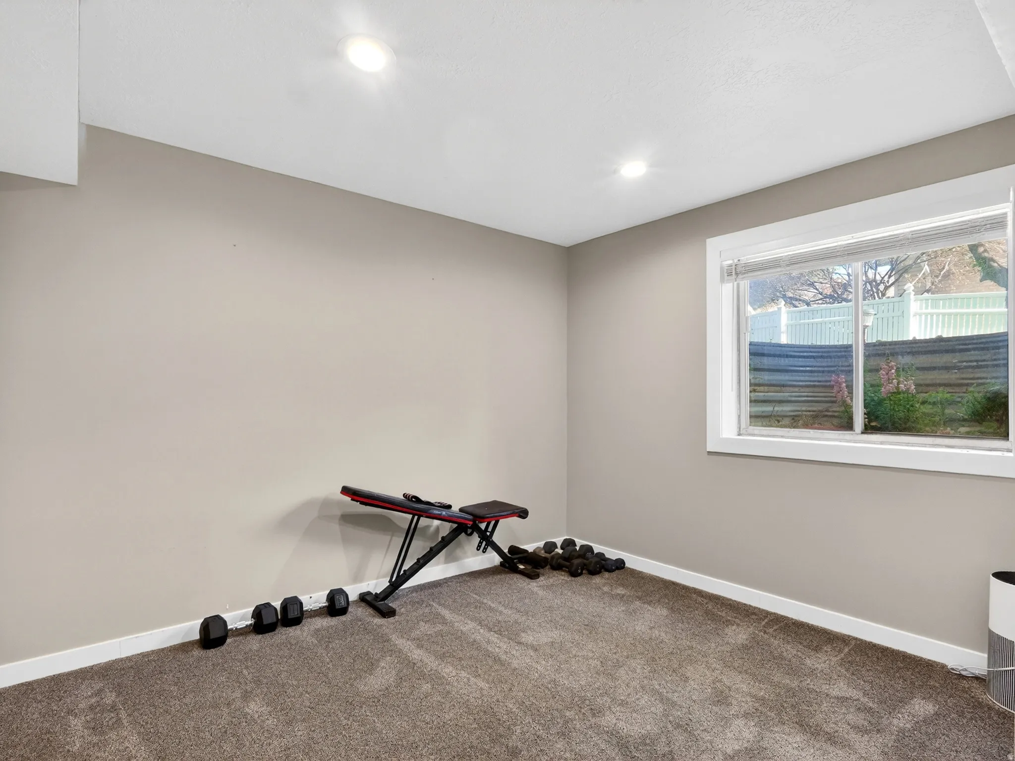 Room featuring a window with white trim, recessed lighting, neutral wall paint, white baseboards, and carpeted flooring
