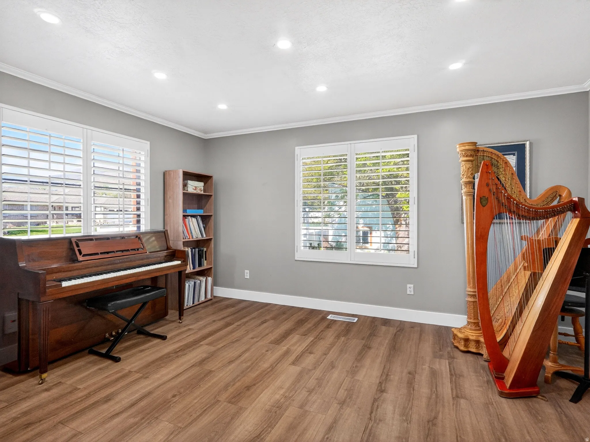 Spacious room featuring wood-finish flooring, light gray walls, and white crown molding