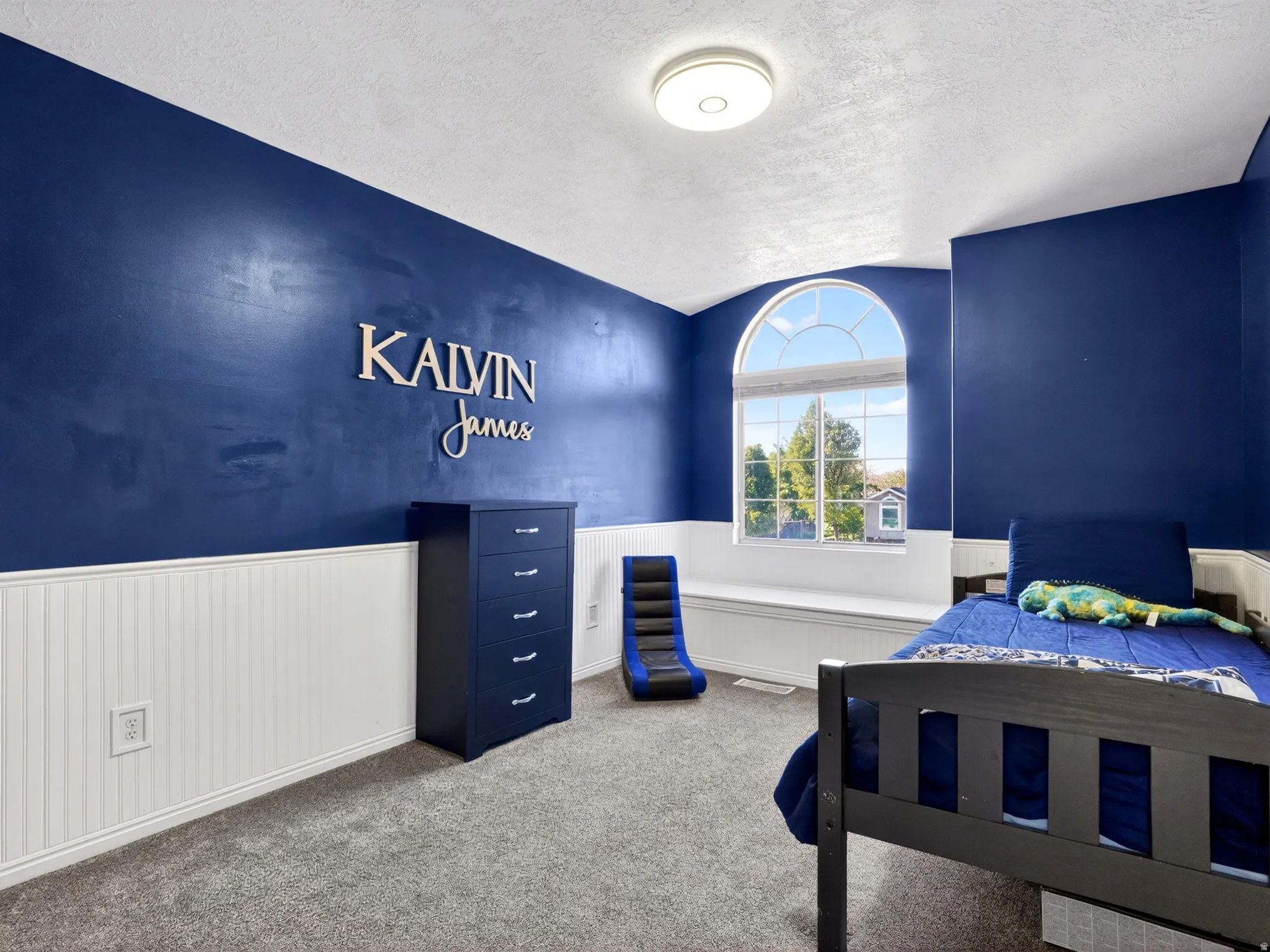 Arch-top window with integrated window seat, complemented by white wainscoting and blue walls
