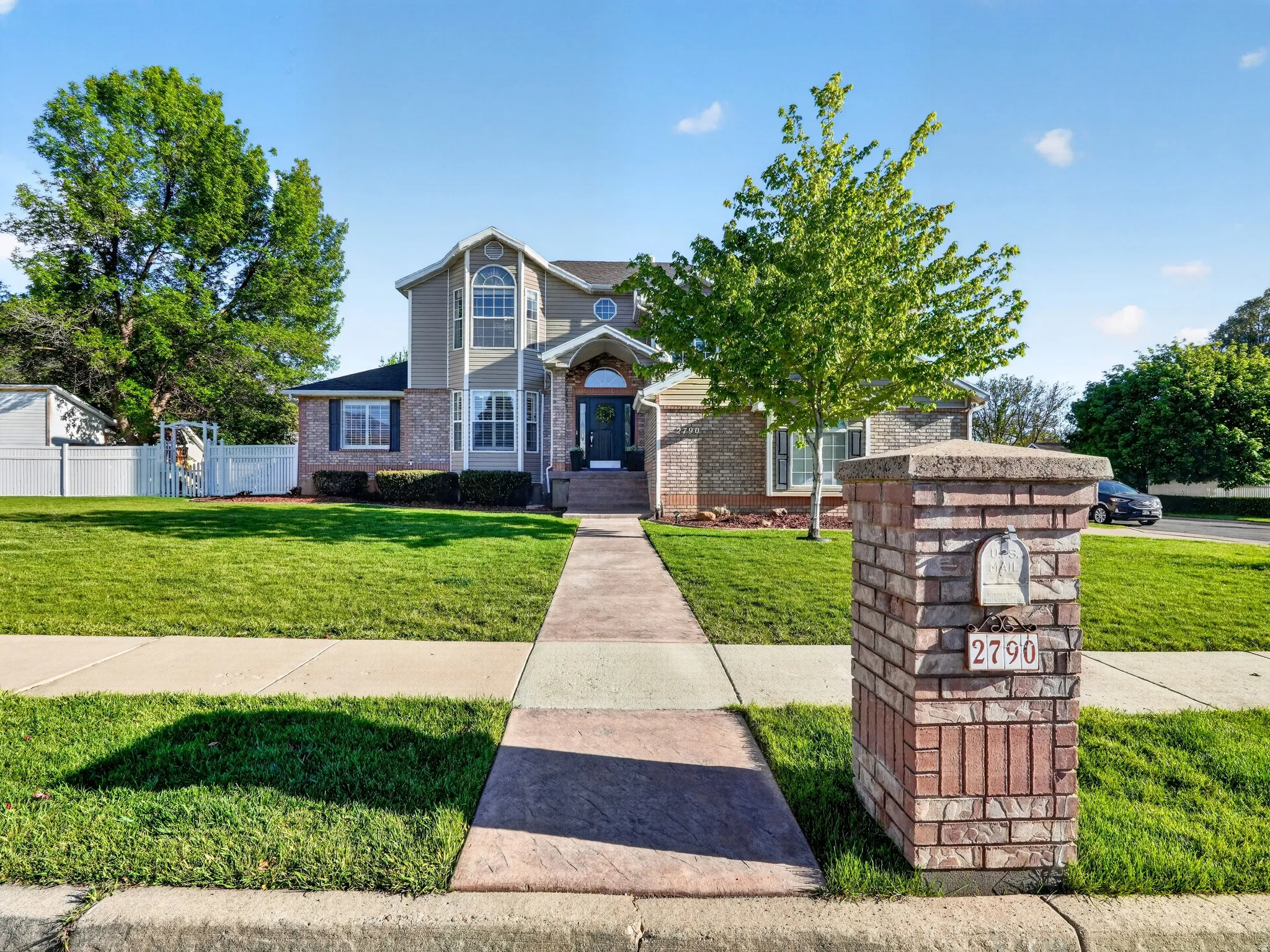 Two-story residence featuring a brick and siding exterior, arched window details, a covered entryway, and a stamped concrete walkway