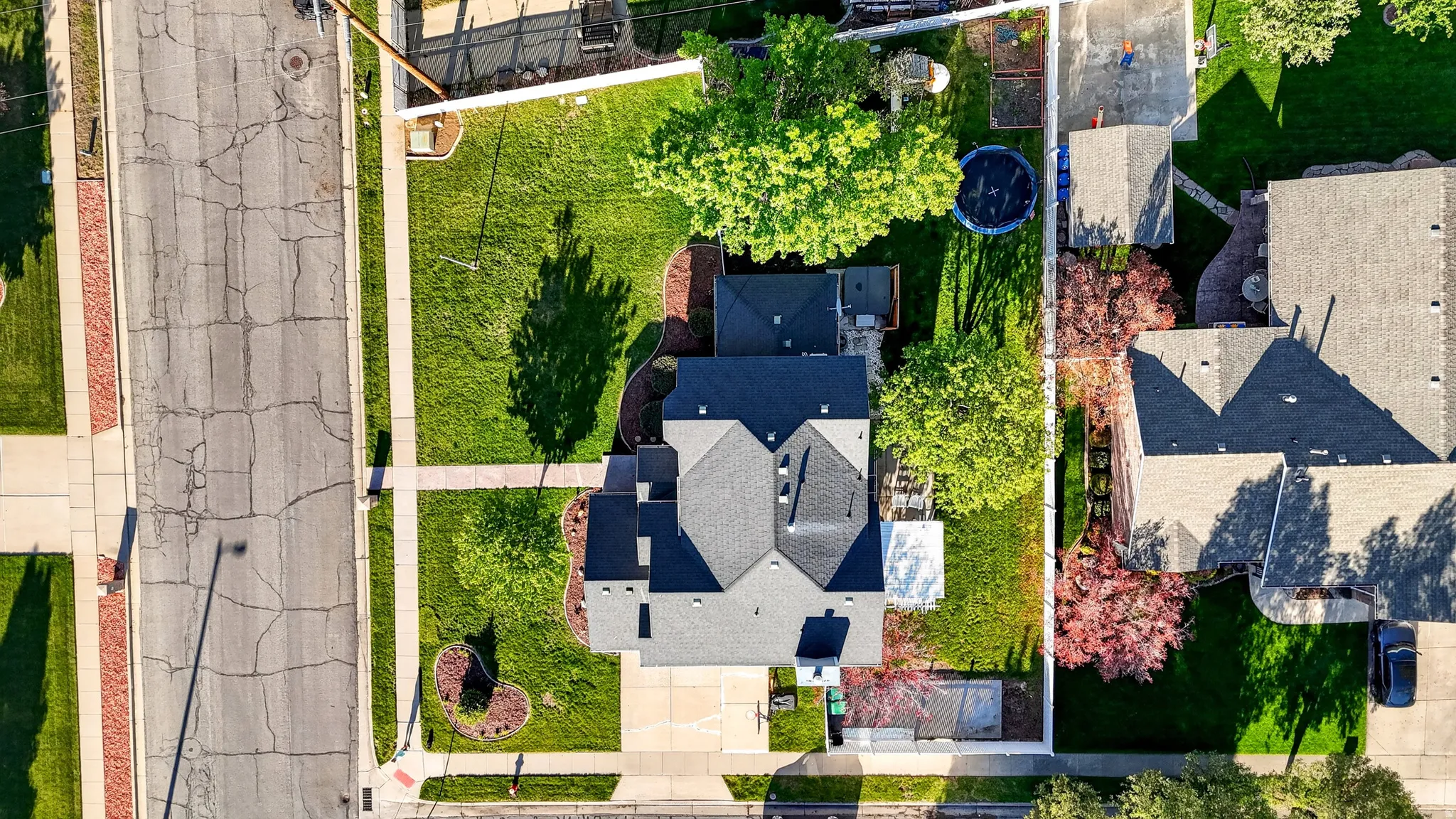 Expansive property featuring a large structure with a dark shingle roof, surrounded by green lawns and mature trees