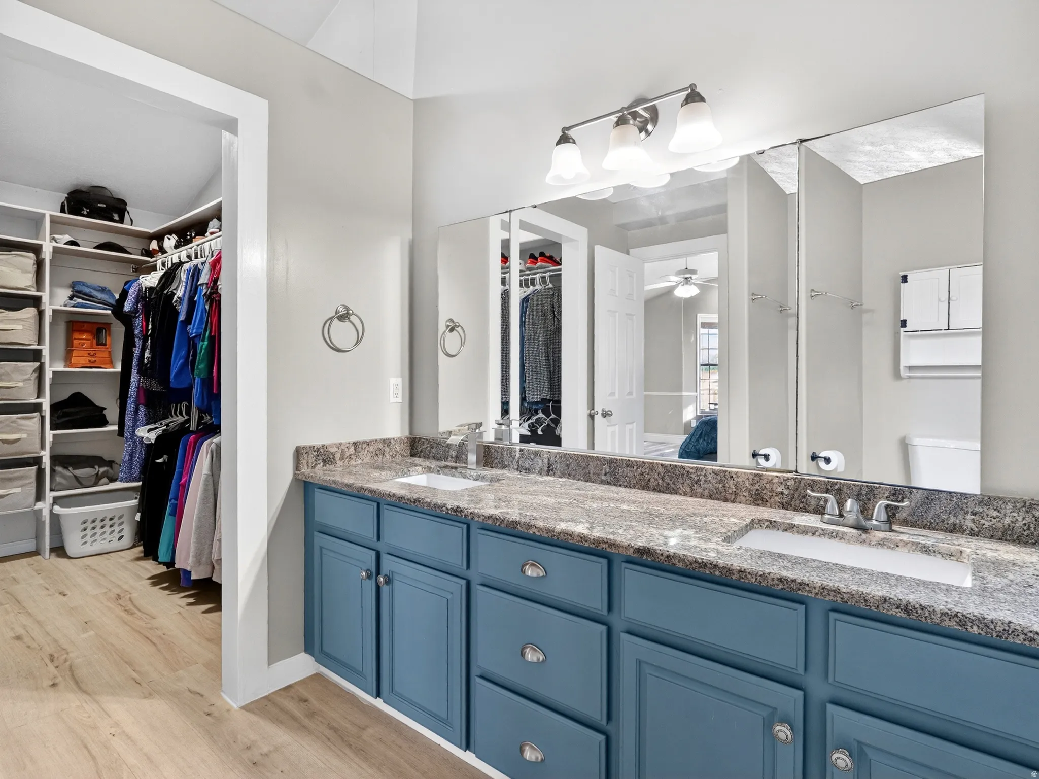 Vanity area featuring a dual sink configuration, a stone-finish countertop, and blue cabinetry with brushed nickel hardware
