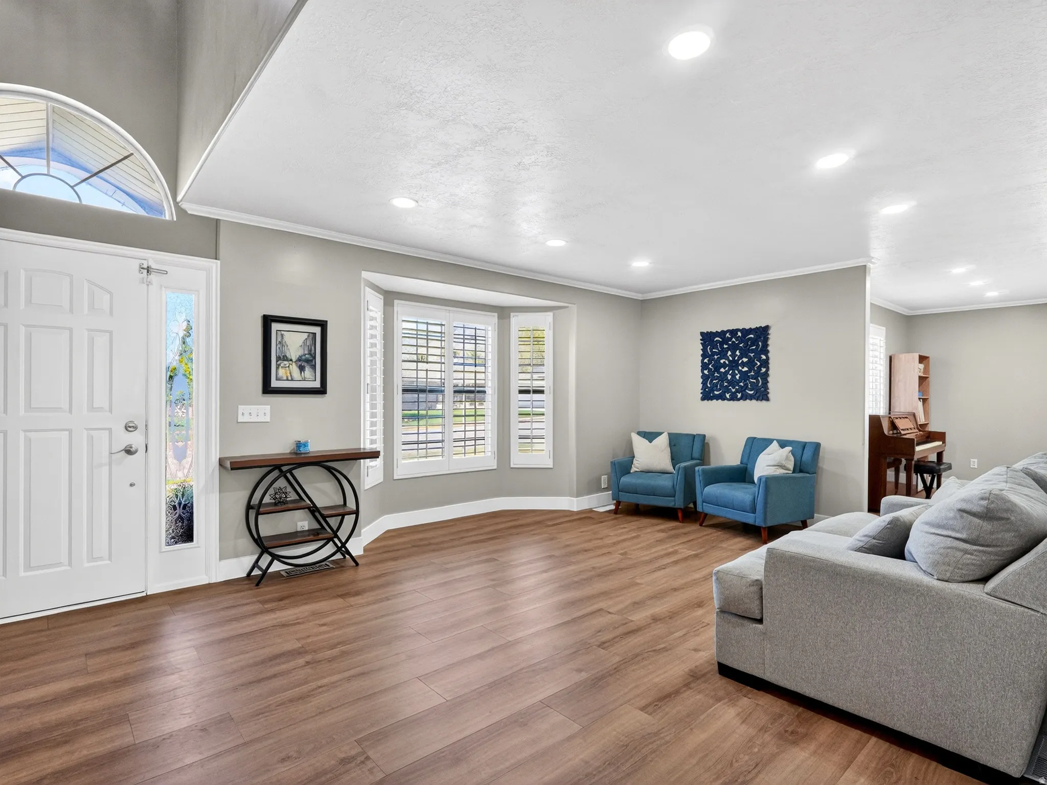 Spacious room featuring wood-finish flooring, recessed lighting, and a bay window with plantation shutters