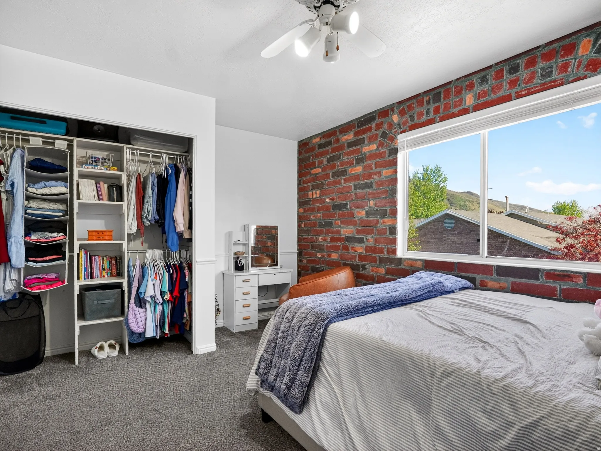 Bedroom featuring an exposed brick accent wall, white trim, and a white ceiling fan