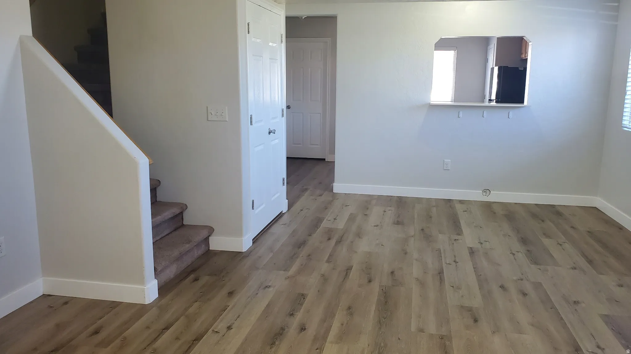 Bright interior space featuring wood-finish flooring, light neutral wall paint, and white baseboards