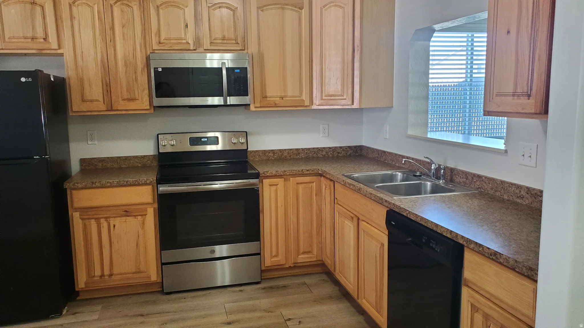 Kitchen featuring wood-finish cabinetry, speckled countertops, and wood-finish flooring