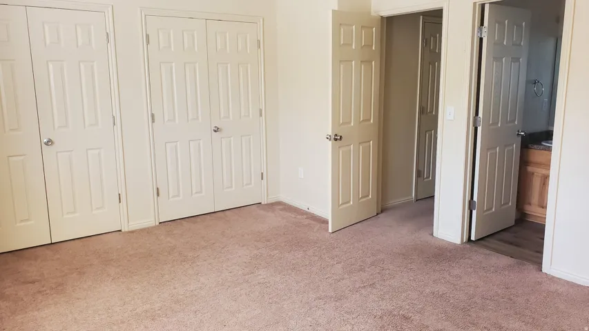 Carpeted room featuring multiple panel doors, neutral wall paint, and white baseboards