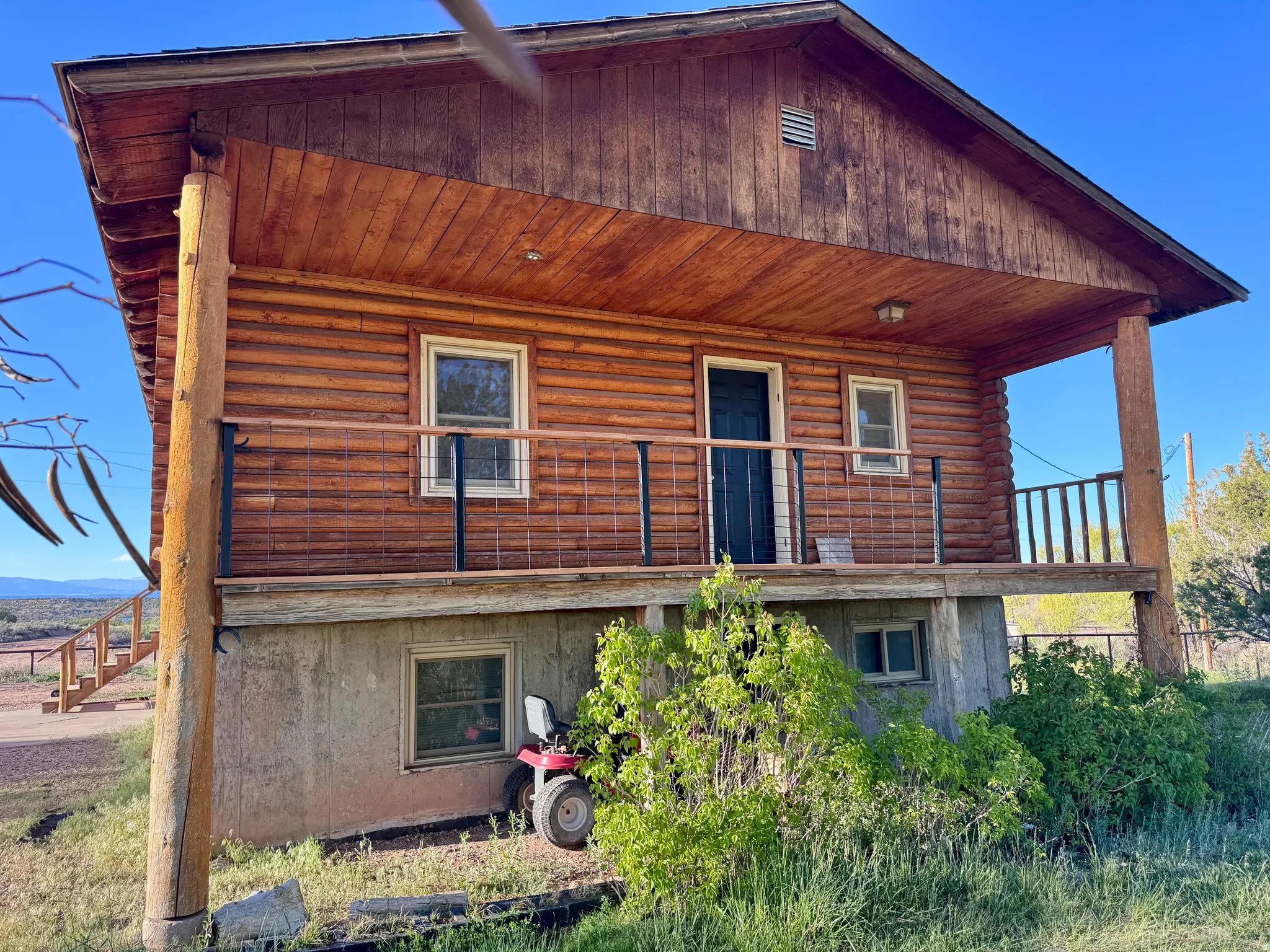 Log cabin exterior with a covered porch featuring wooden posts and a metal railing
