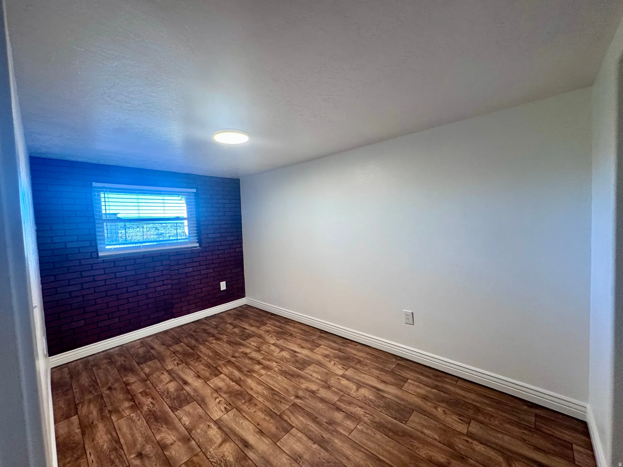 Interior room featuring wood-finish flooring and a distinctive dark brick accent wall
