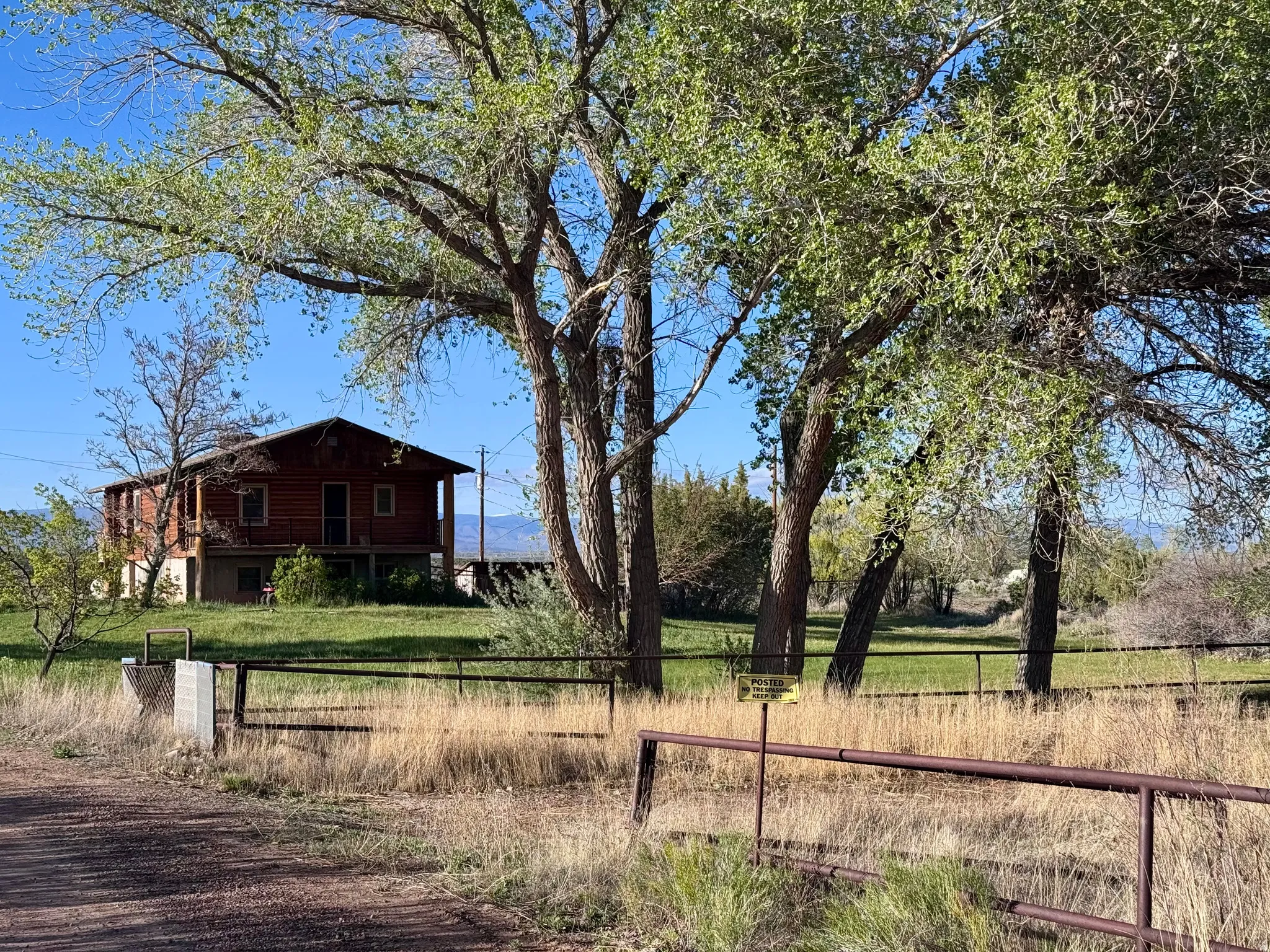 Wood-sided dwelling featuring an upper-level porch and a metal roof, situated on a grassy landscape