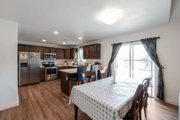 Open-concept kitchen and dining area featuring wood-finish flooring, recessed lighting, and a sliding glass door