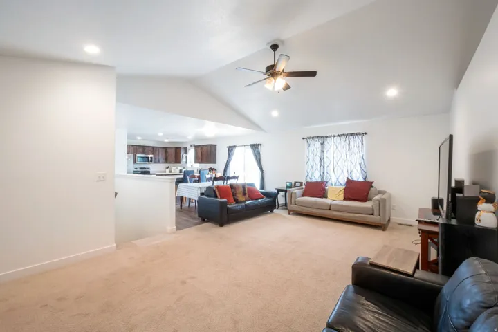 Open concept living area featuring vaulted ceilings, recessed lighting, and a ceiling fan