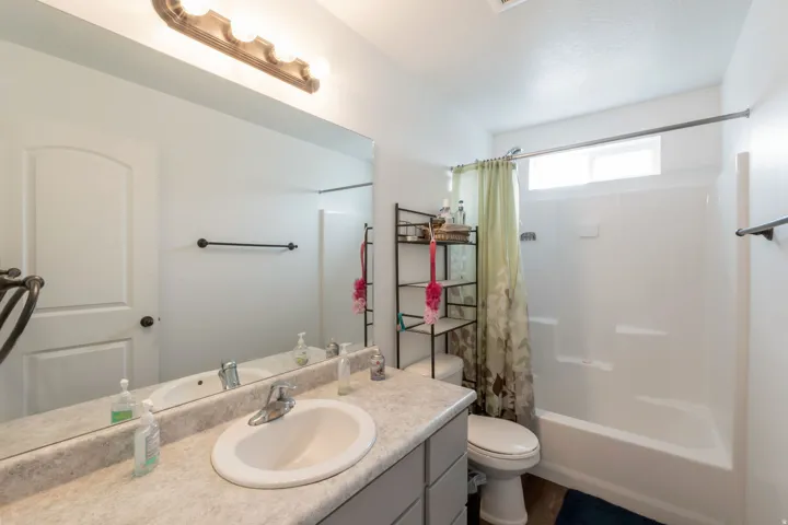 Bathroom featuring a vanity with an integrated sink, a large wall-mounted mirror, and a three-bulb light fixture
