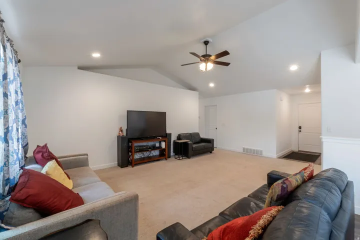 Spacious living area featuring vaulted ceilings, recessed lighting, and a ceiling fan