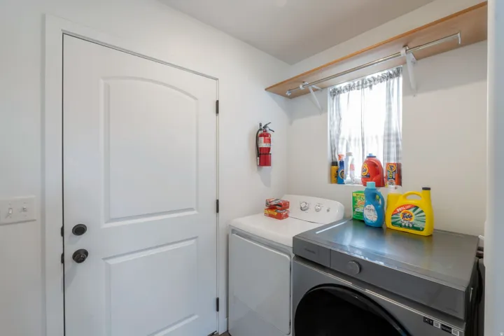 Laundry area featuring a window, wood-finish shelving, and a hanging rod