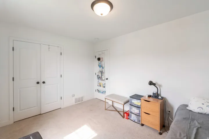 Neutral carpeted room featuring white walls and a white ceiling with a flush-mount light fixture