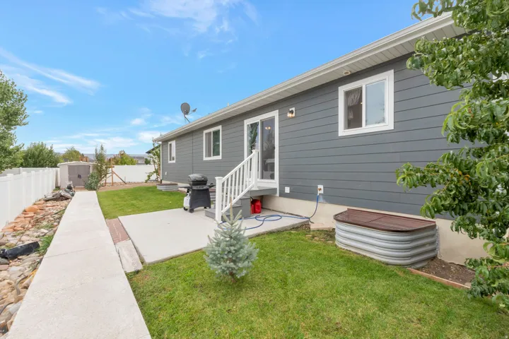 Rear exterior featuring gray siding, white trim, and a white fence