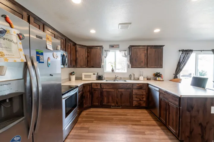 U-shaped kitchen featuring wood-finish cabinetry, light-toned countertops, and wood-finish flooring