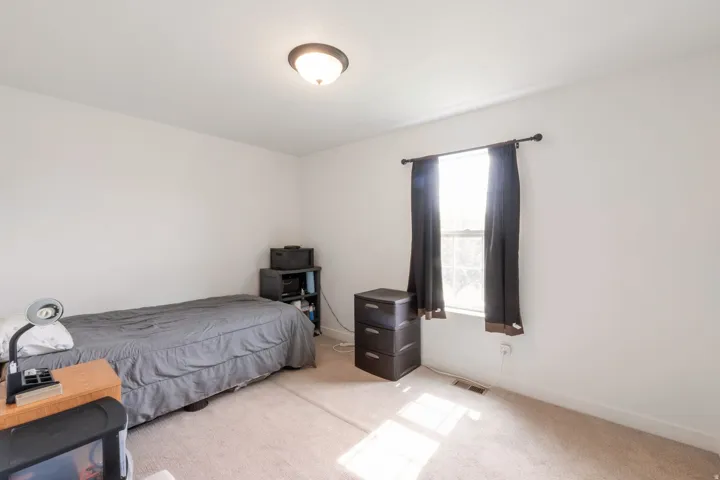 Bright room featuring a window with dark curtains, light neutral carpeting, and white walls