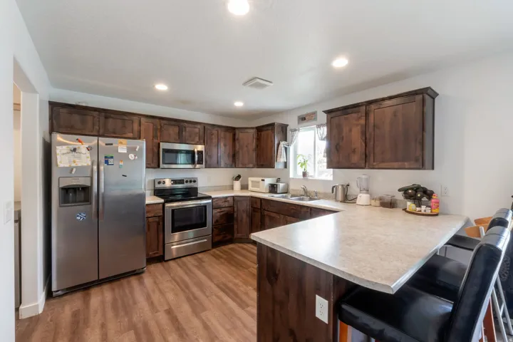 Kitchen featuring dark wood cabinetry, light countertops, and stainless steel appliances