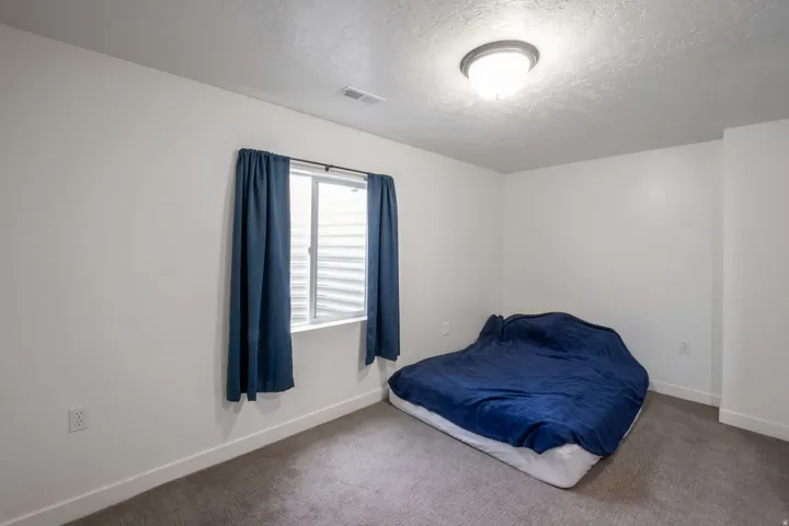 Room featuring a window with blinds, a flush mount ceiling light fixture, a carpeted floor, and white walls with white baseboards
