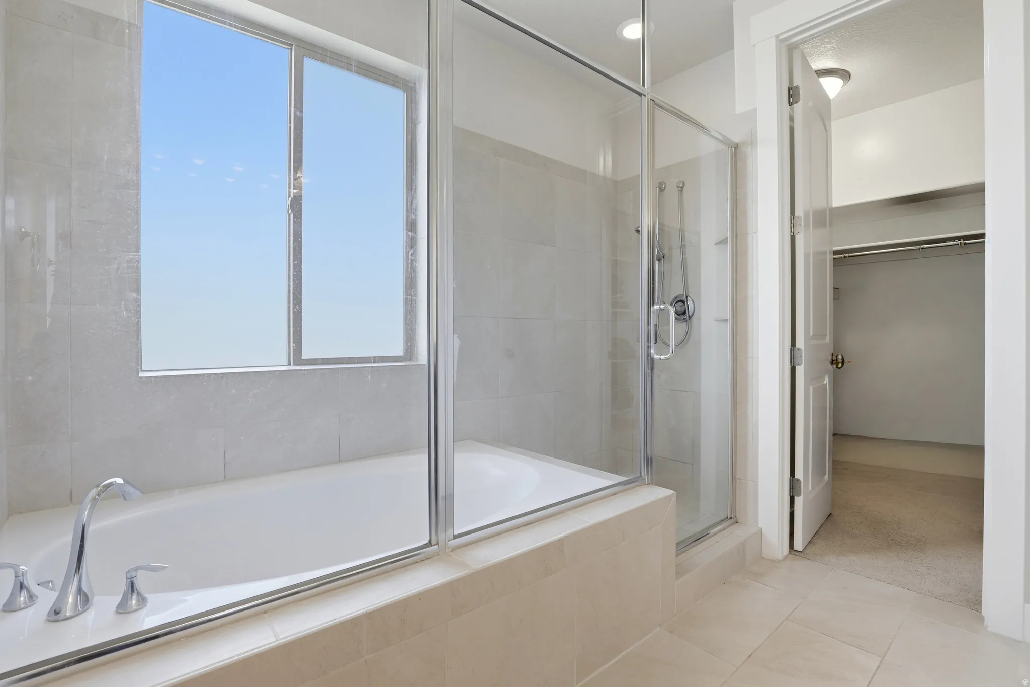 Bathroom featuring an integrated soaking tub and separate glass-enclosed shower with tiled surround
