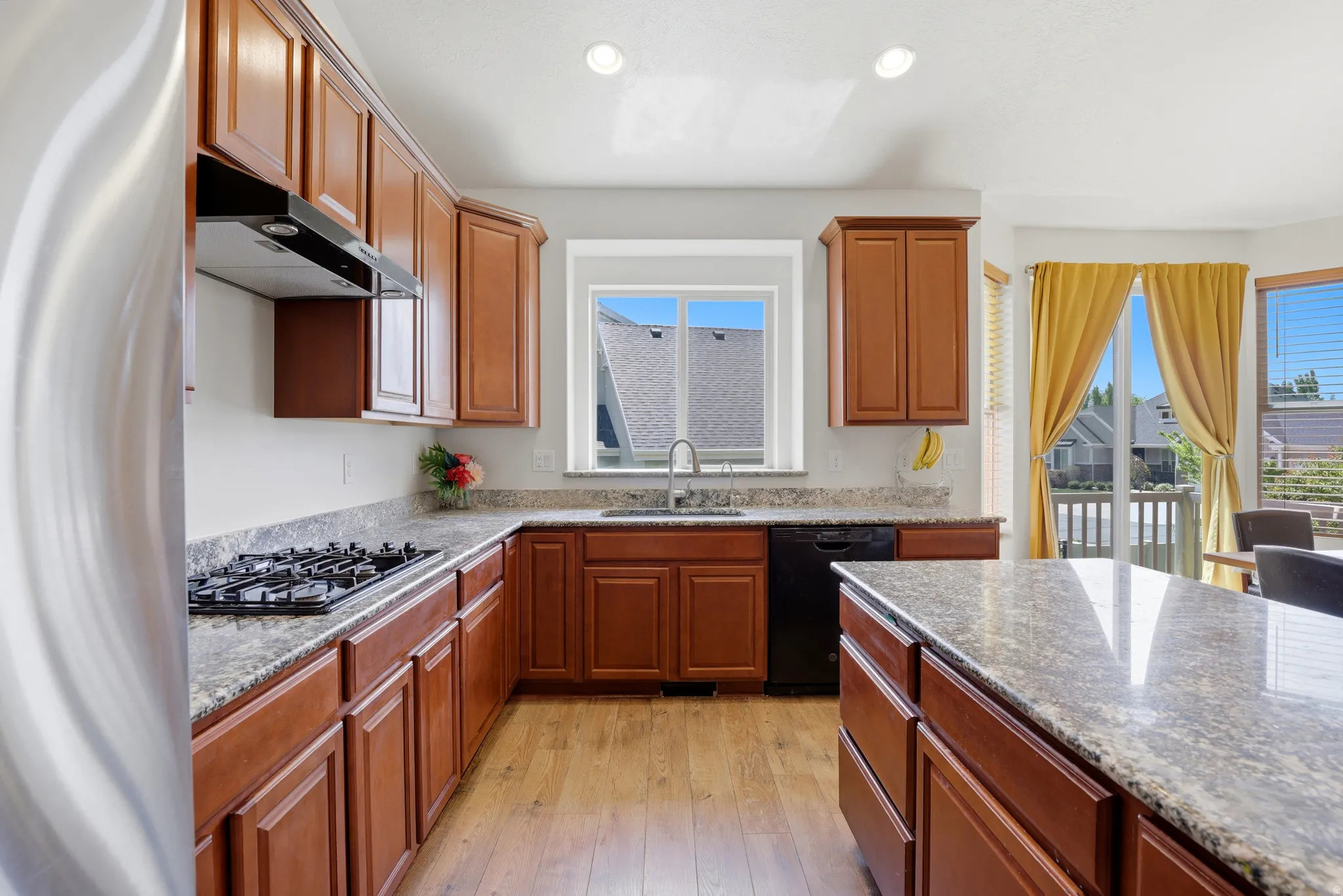 Kitchen featuring wood-finish flooring, ample wood cabinetry, and granite countertops