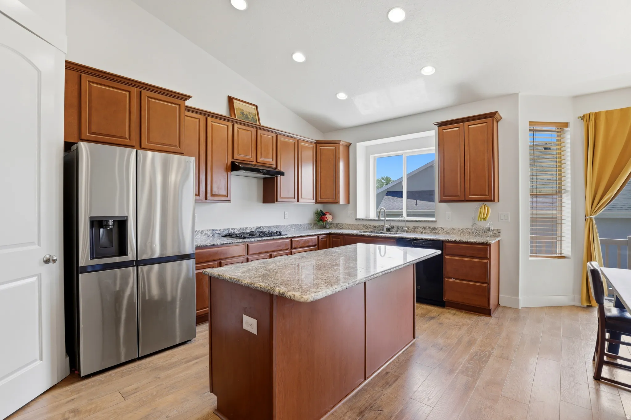 Open-concept kitchen featuring wood-finish flooring, recessed lighting, and a vaulted ceiling