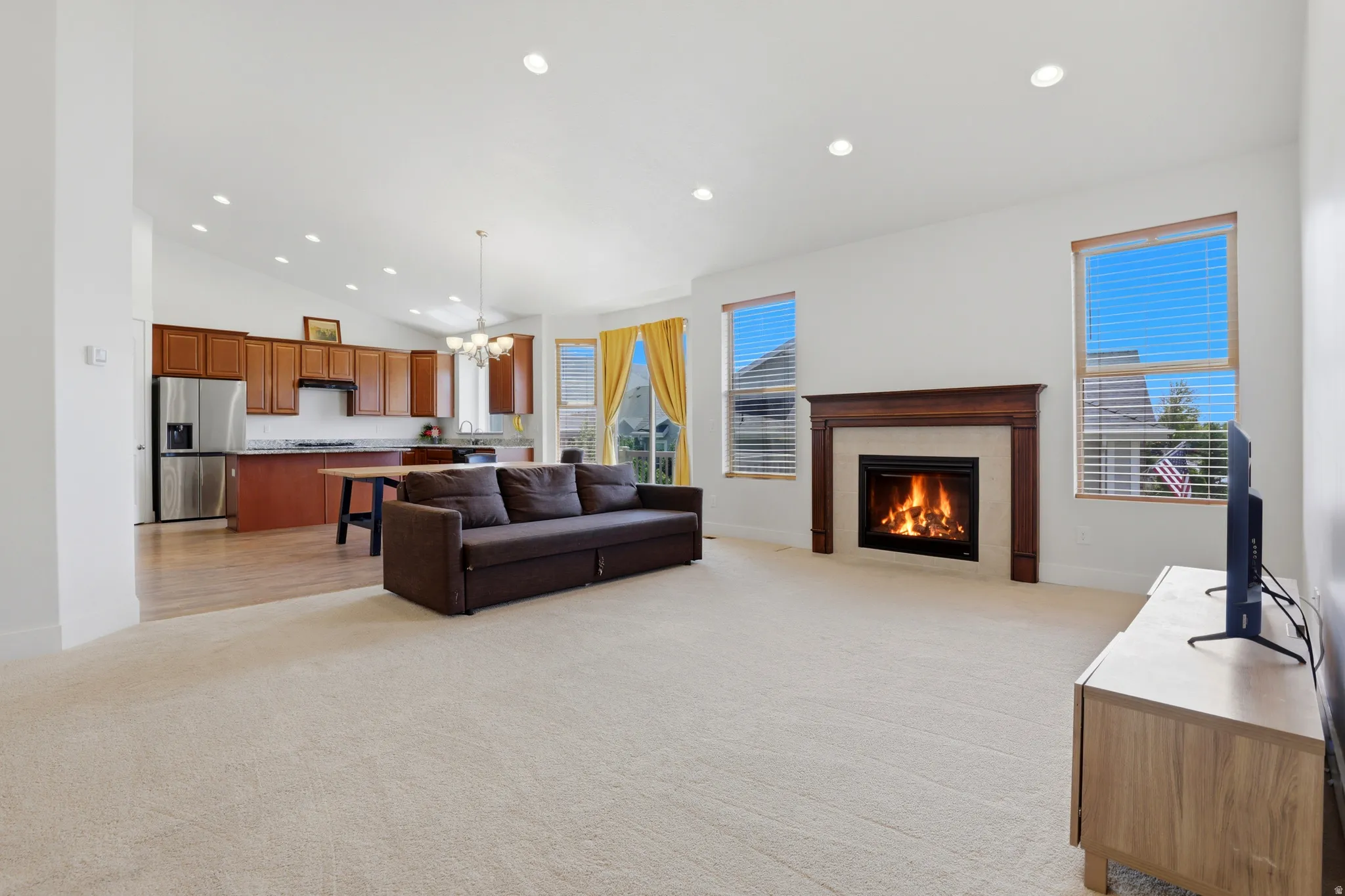 Expansive living area featuring a gas fireplace with wood mantel and tile surround, vaulted ceiling, and recessed lighting