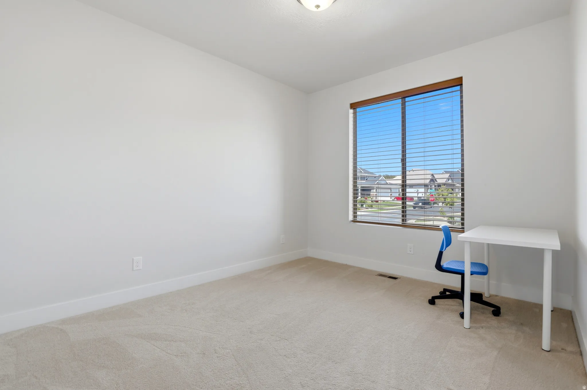 Neutral-toned wall finishes with a single window featuring wood-look trim and horizontal blinds