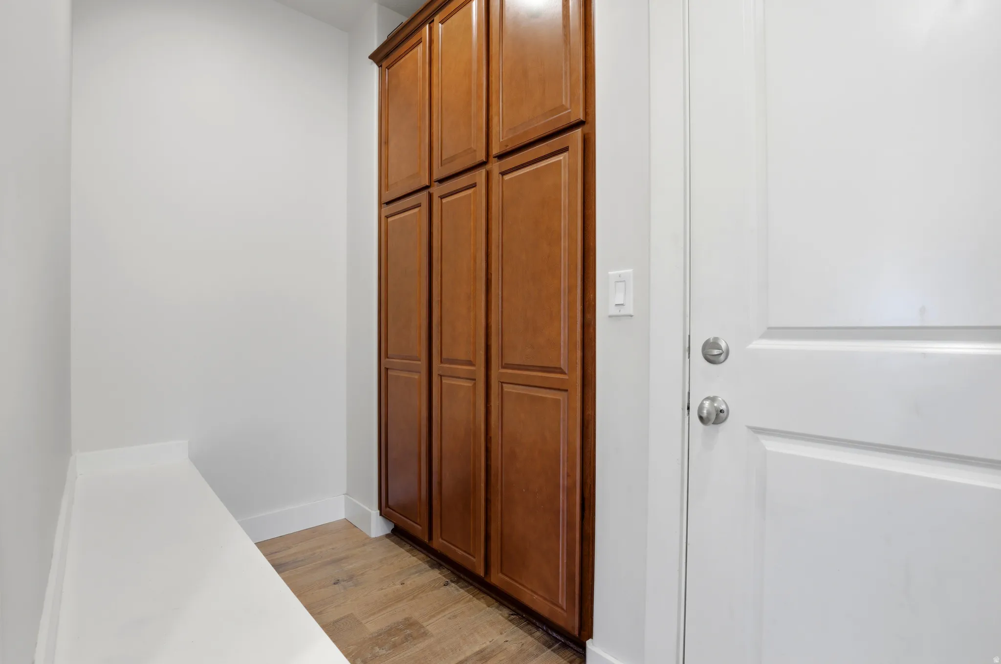 Entryway featuring a built-in bench, wood-finish flooring, and floor-to-ceiling cabinetry