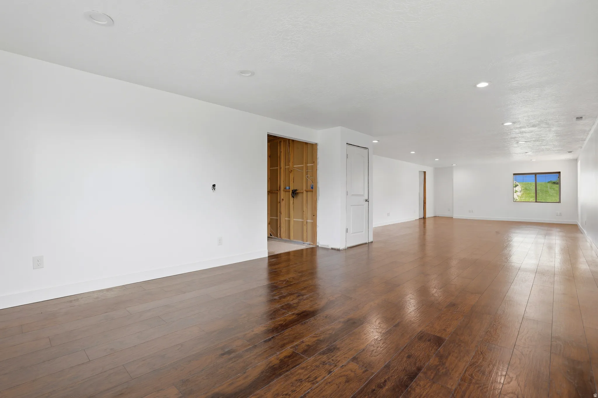 Spacious room featuring wood-finish flooring, recessed lighting, and a neutral color palette