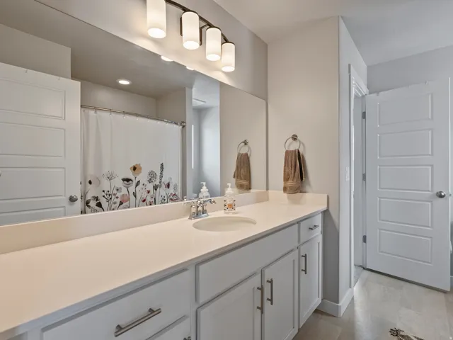 White vanity with brushed nickel hardware, integrated sink, and a large mirror