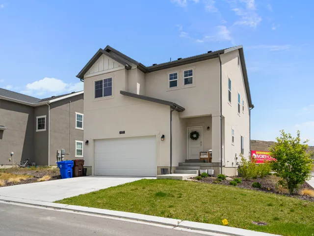 Contemporary two-story residence featuring a stucco exterior, an attached front-facing garage, and a covered entryway