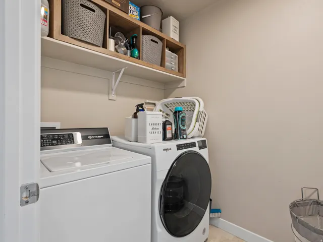 Dedicated laundry area featuring overhead shelving, light-toned walls, and tile flooring