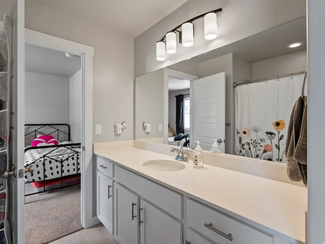 Bathroom featuring a spacious vanity with an integrated sink, light-colored countertop, and ample storage cabinets