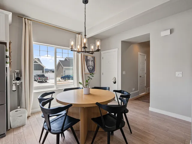 Dining area featuring wood-finish flooring, a contemporary chandelier, and a large window with white trim