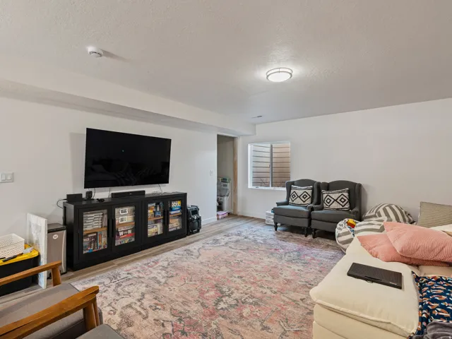 Spacious room featuring wood-finish flooring, recessed lighting, and a window with horizontal blinds