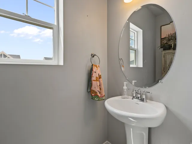 Pedestal sink with chrome fixtures and an oval wall mirror