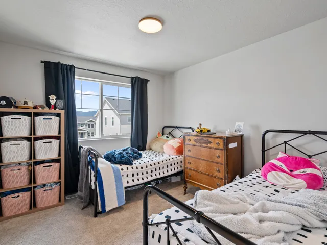 Bright room featuring a window with dark curtains, a built-in shelving unit with storage baskets, and light-colored carpet