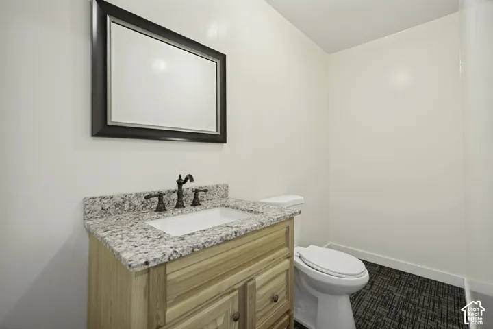 Bathroom featuring a natural wood vanity with a stone countertop and an integrated white sink