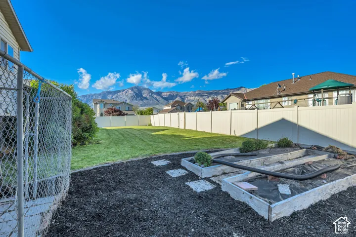 Expansive backyard featuring a manicured lawn, white privacy fencing, and raised garden beds