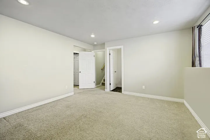 Carpeted room featuring recessed lighting, a window with horizontal blinds, and multiple doorways
