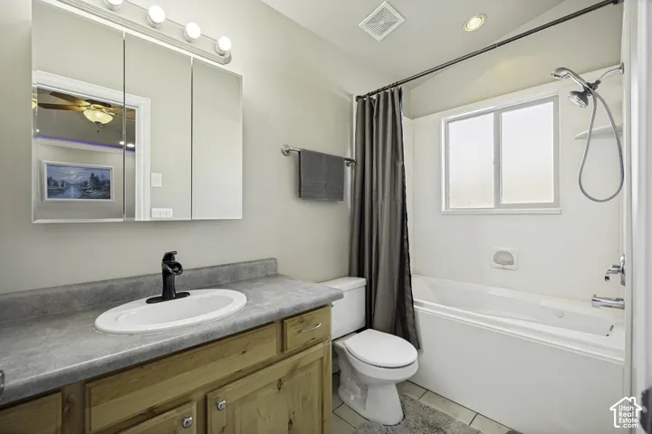 Full bathroom featuring a single vanity with wood cabinetry, a light-toned countertop, and an oval undermount sink with a black faucet