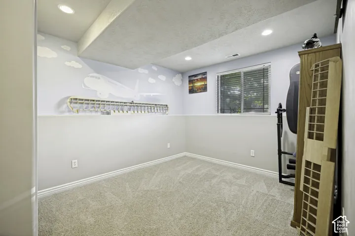 Carpeted room featuring recessed lighting, a window with horizontal blinds, and a two-tone wall treatment with a decorative airplane mural