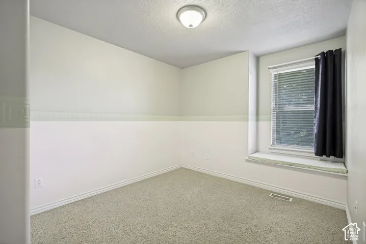 Neutral painted walls with chair rail detailing, light-colored carpeting, a single window with blinds, and a built-in window seat
